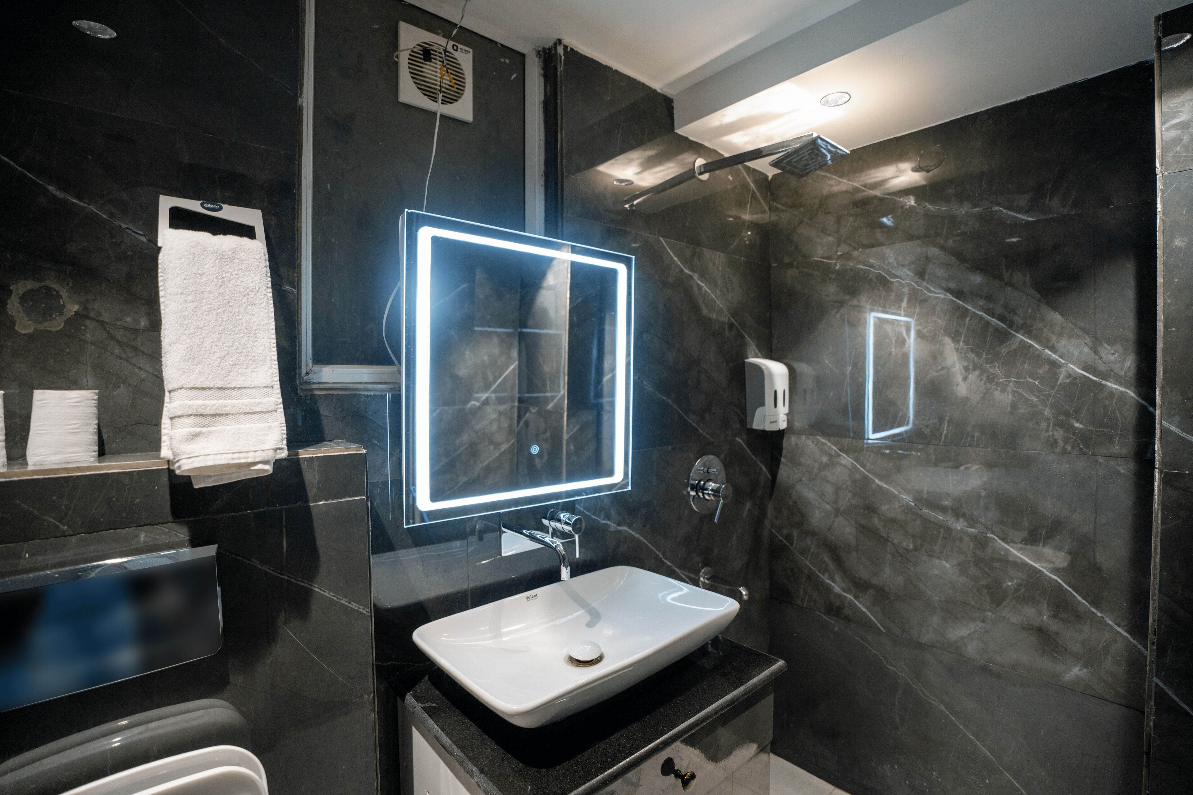 A modern bathroom with a large mirror, a white sink, and a shower.