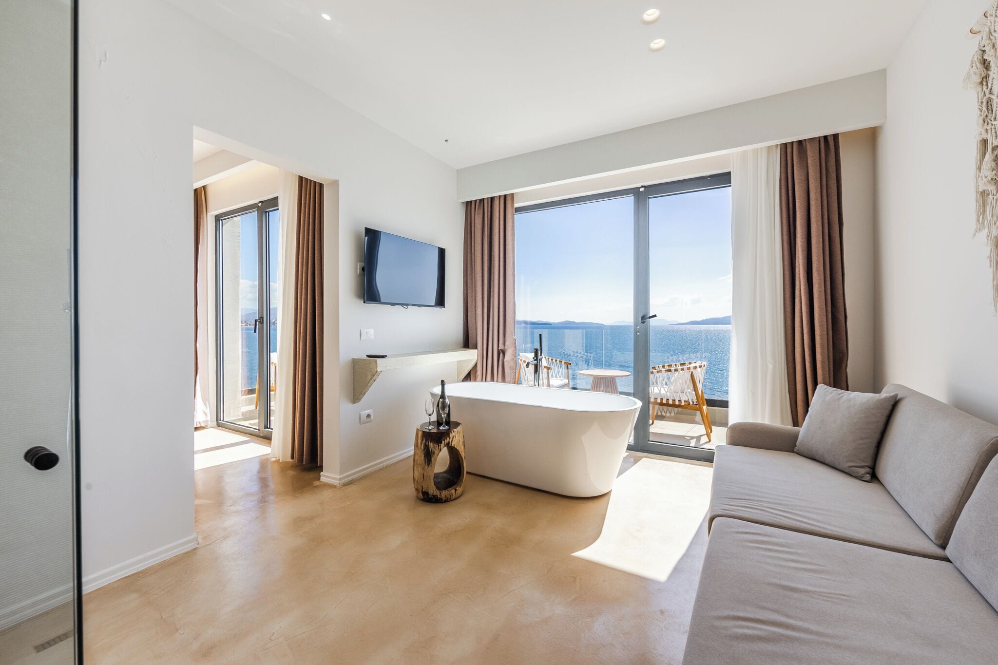 Ein modernes Hotelzimmer mit einer großen Badewanne, einer Couch und einem Fernseher.