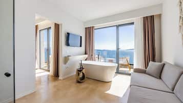 Ein modernes Hotelzimmer mit einer großen Badewanne, einer Couch und einem Fernseher.