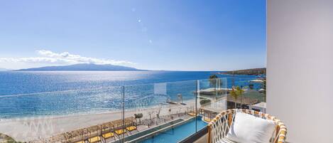 Un balcón con vista al mar, una piscina y una zona de estar.