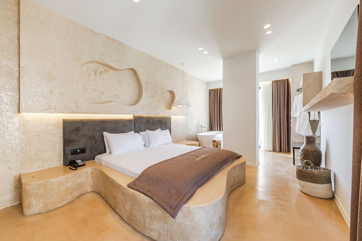 Een moderne slaapkamer met een rond bed, een groot hoofdeinde en een minimalistisch design.