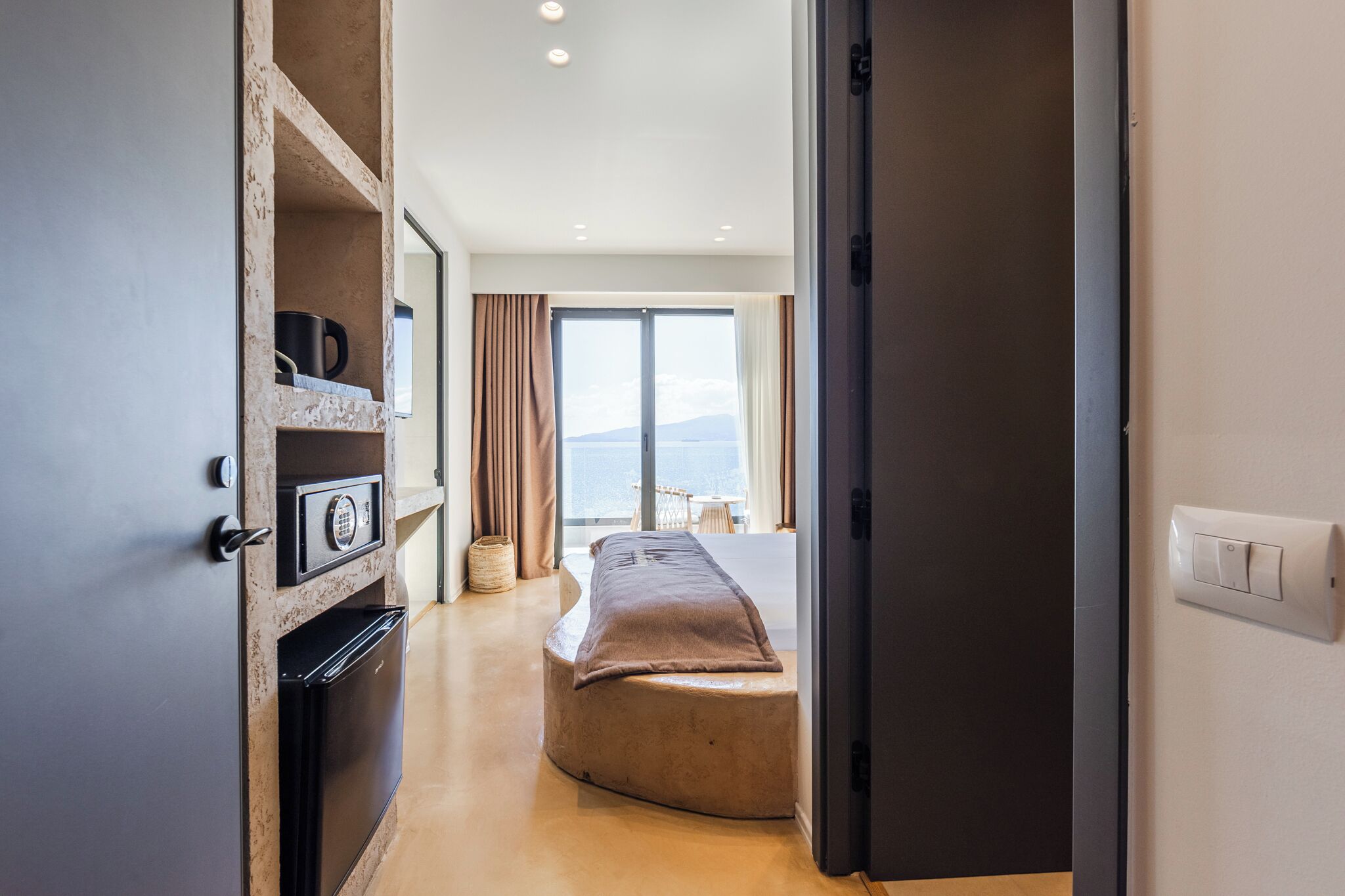 Una habitación de hotel moderna con horno integrado, un rincón de descanso acogedor y un ventanal con vistas panorámicas.