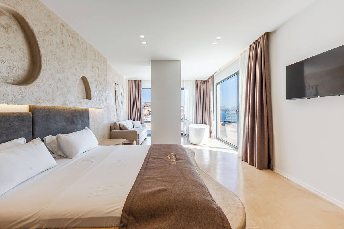 Een moderne hotelkamer met een groot bed, een flatscreen televisie en uitzicht op de stad.