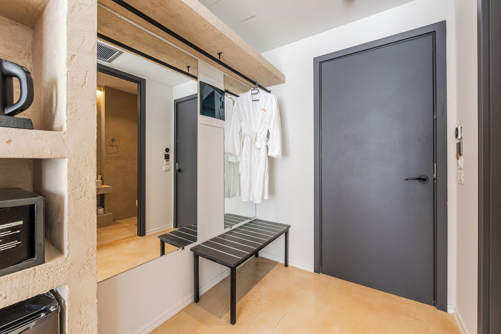 Une salle de bain moderne avec un miroir, un porte-serviettes et un banc.