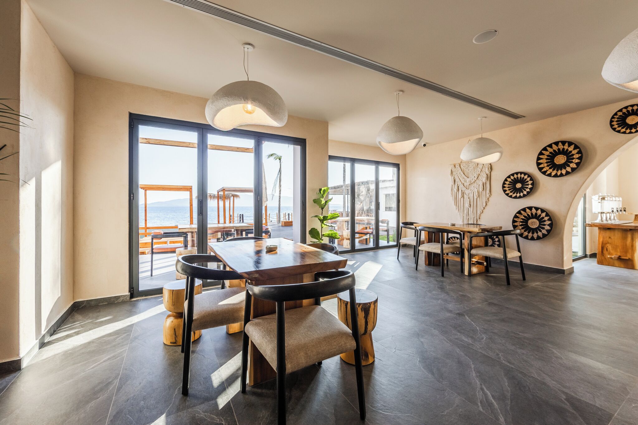 A spacious dining area with a large table, chairs, and pendant lights.