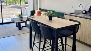 Une cuisine moderne avec un coin repas, de grandes fenêtres et une vue sur l’extérieur.