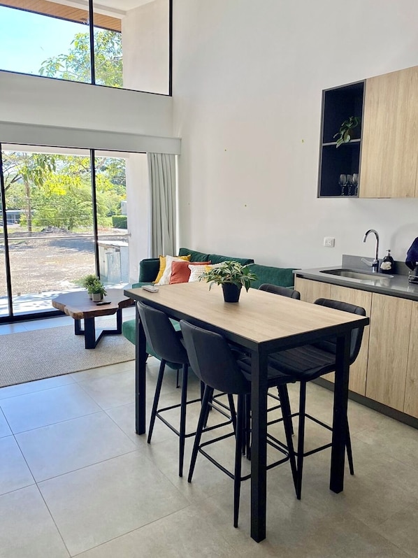 A modern kitchen with a dining area, large windows, and a view of the outdoors. - Exclusive Beach and Golf in Blue Zone (Provincia de Puntarenas)