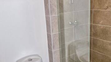 Ein Badezimmer mit Toilette, einer Duschkabine und Fliesenwänden.