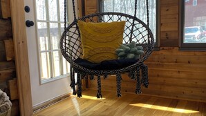A wooden interior with a hanging chair, a door, and a window. - Family Friendly Log Cabin Nestled in Blue Ridge Foothills (Stuarts Draft)
