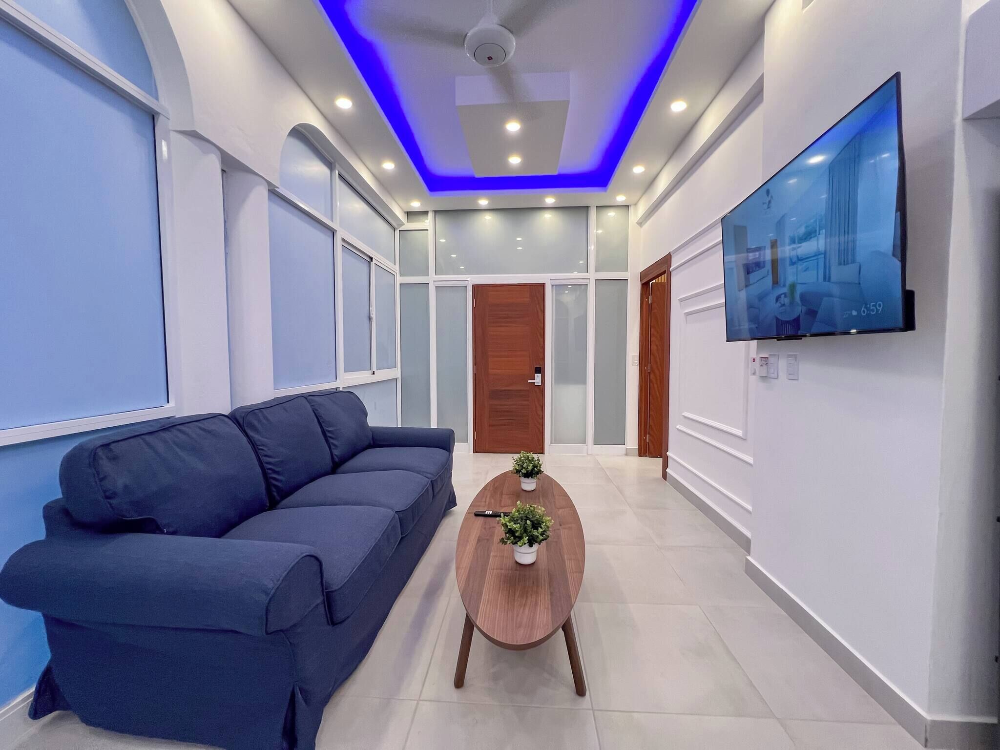 A modern interior with a blue sofa, a wooden coffee table, and a TV mounted on the wall.