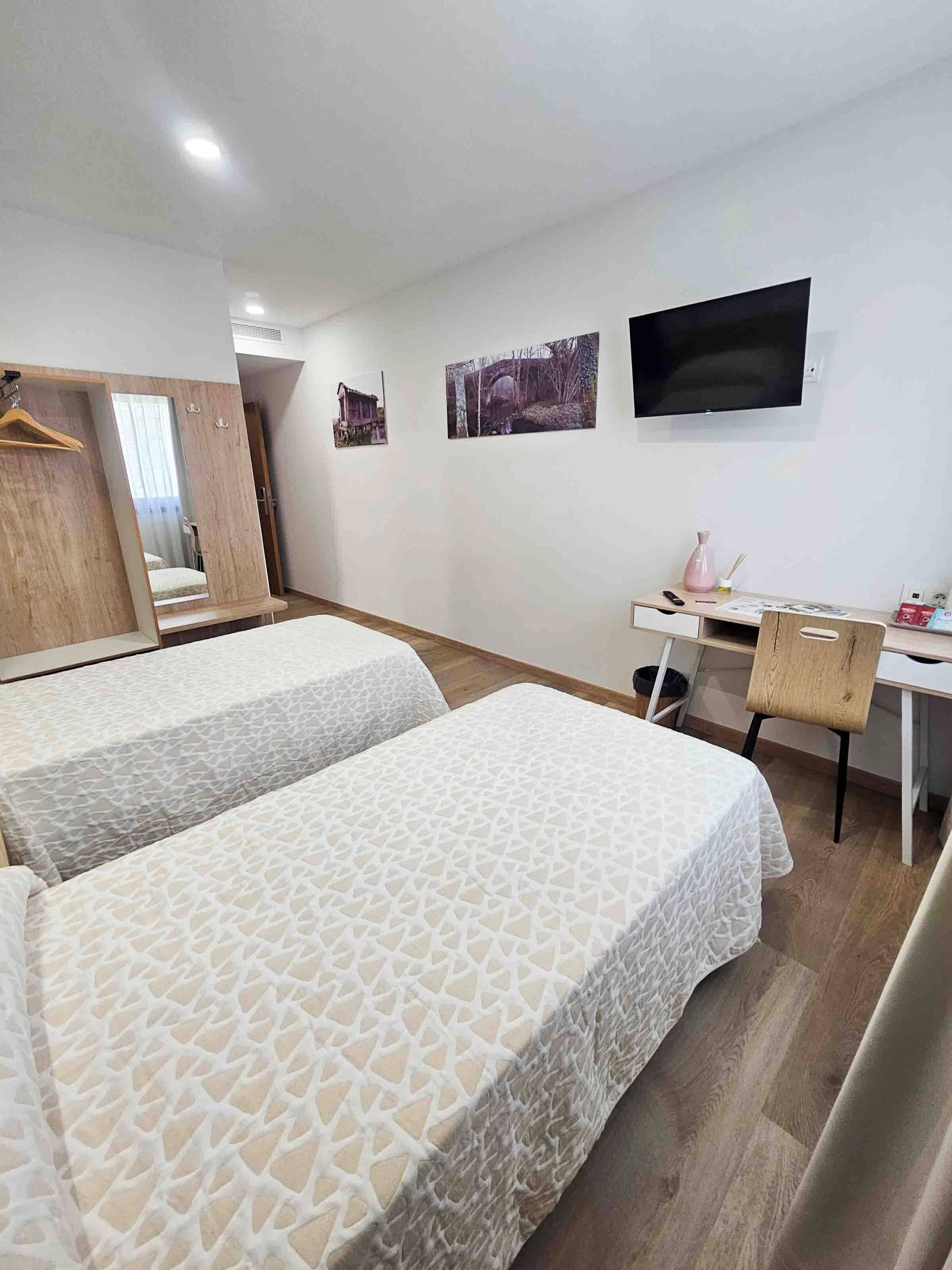 Een hotelkamer met twee bedden, een bureau, een stoel, een televisie en een spiegel.