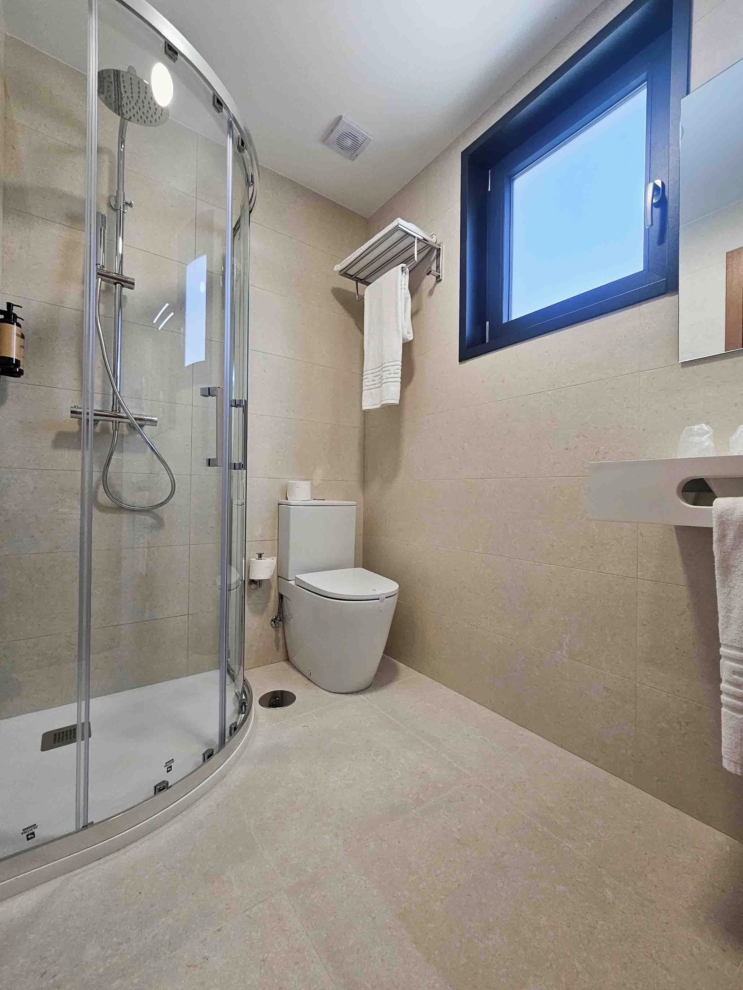 A modern bathroom with a glass-enclosed shower, a toilet, and a sink.