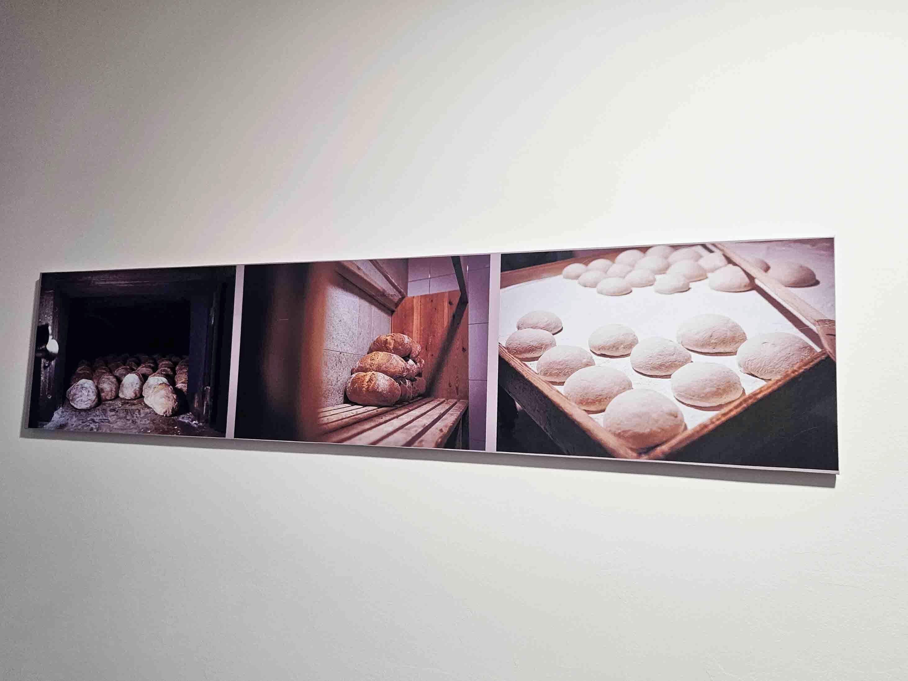 Un mur orné de trois photographies encadrées représentant des scènes de préparation du pain.
