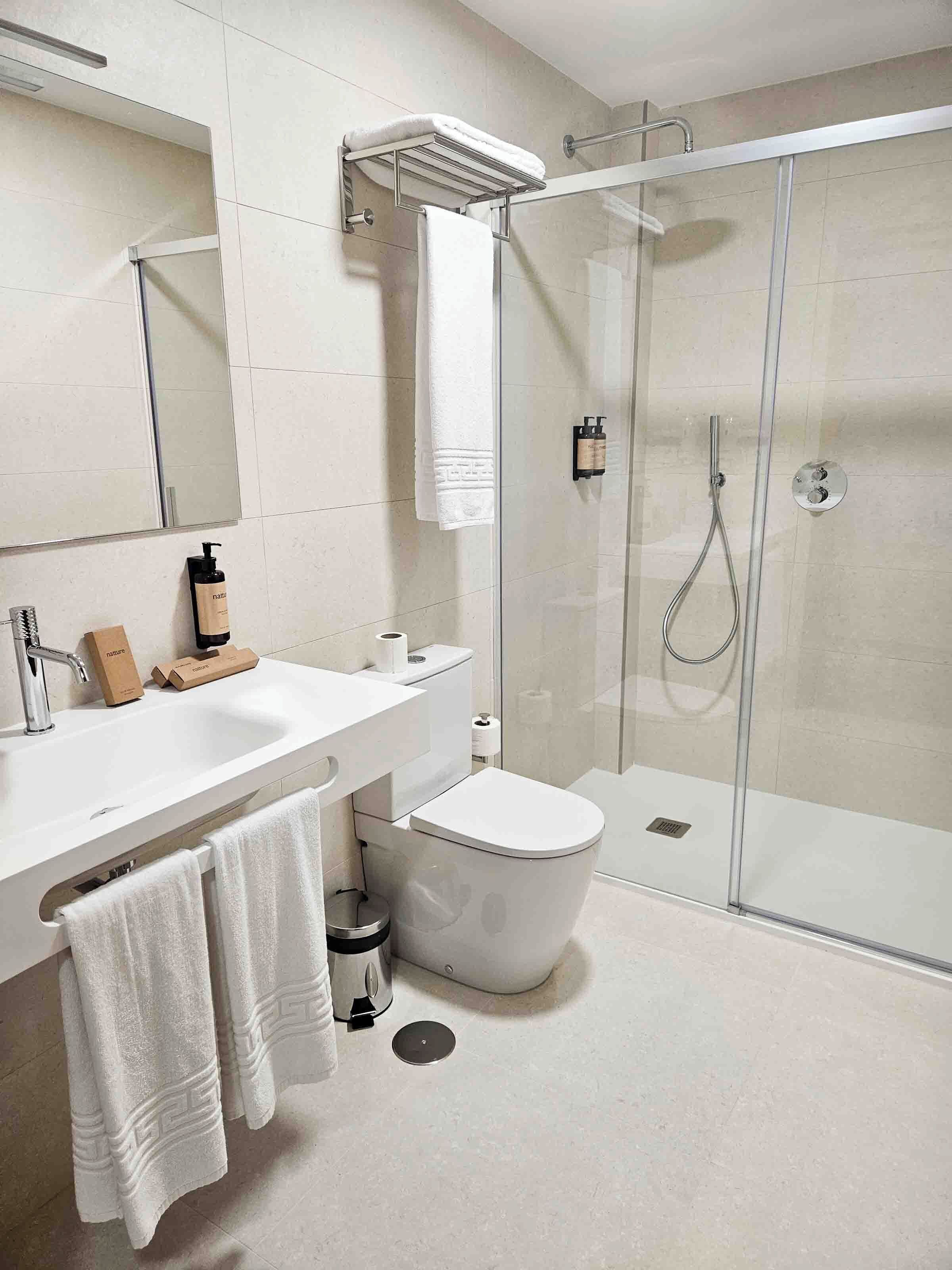 A modern bathroom with a glass-enclosed shower, a white sink, and a toilet.