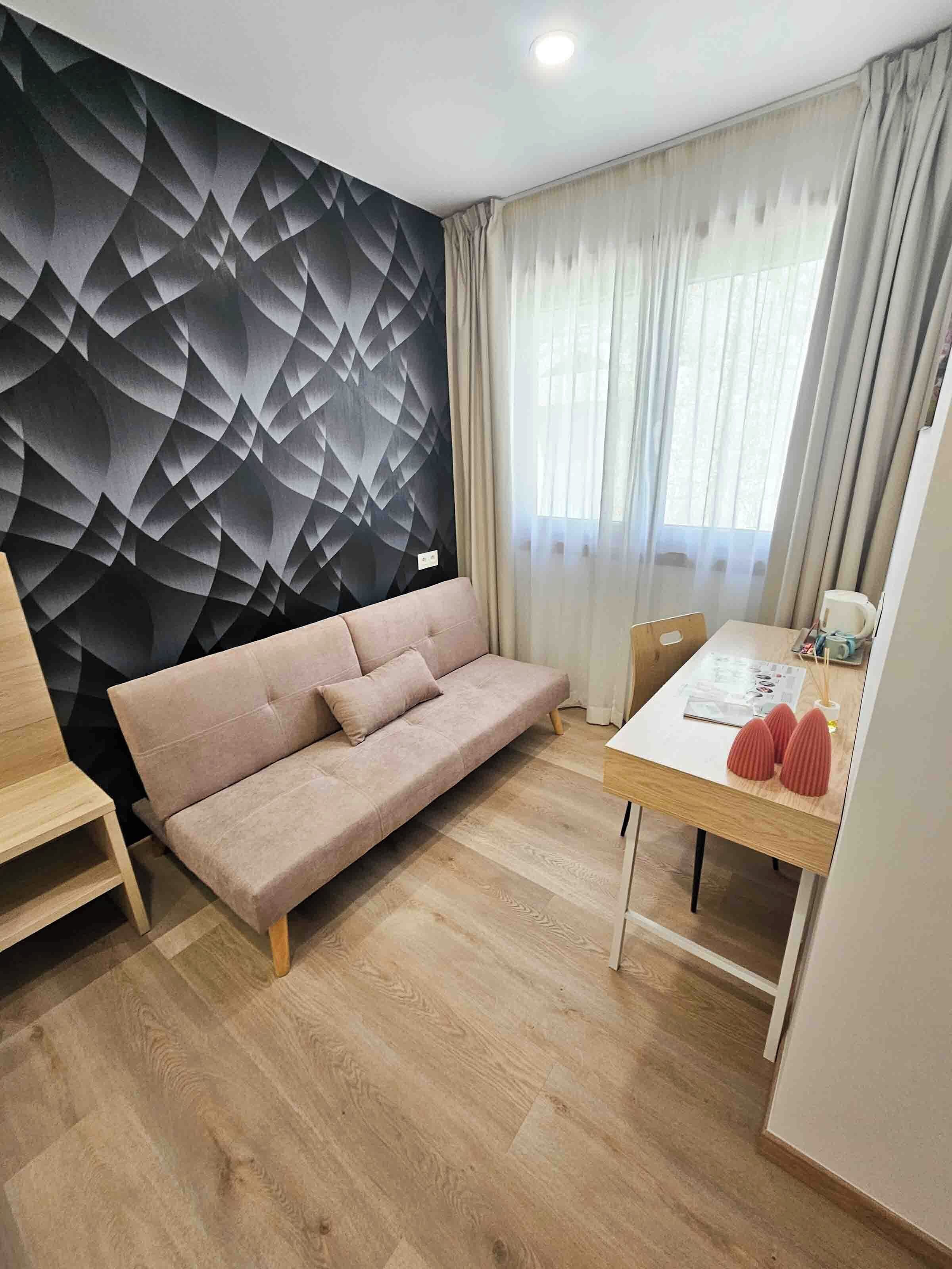 Una sala de estar moderna con un sofá, una mesa de comedor y una pared con estampado geométrico.