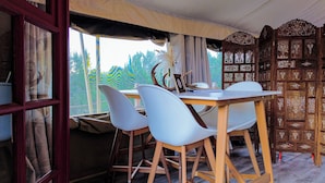 A dining area with a table and chairs, a window with curtains, and a decorative wooden screen. - Lost Horizon Texas (Kempner)