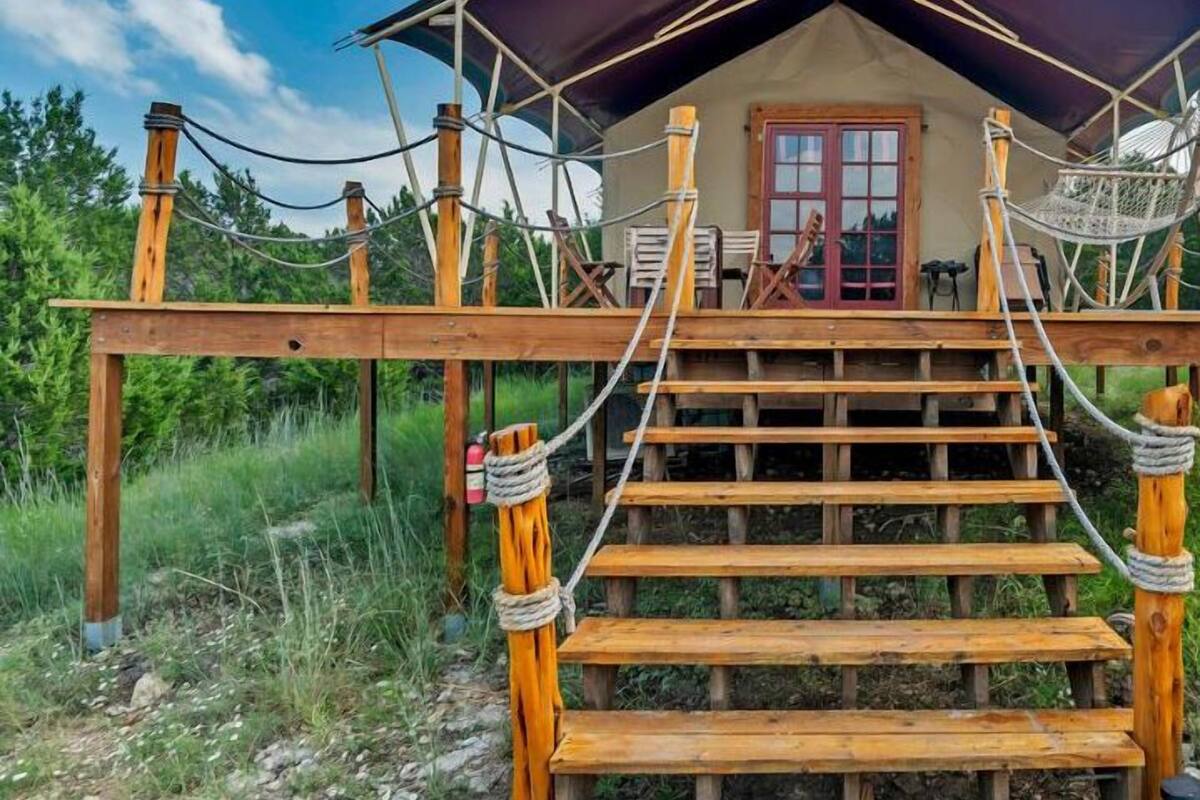 Una terraza de madera que conduce a un edificio con una puerta roja y un porche cubierto.