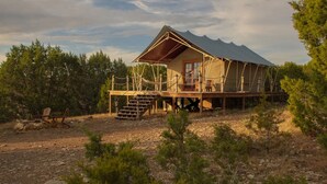A rustic cabin with a wooden deck and a staircase leading to a porch. - Lost Horizon Texas (Kempner)
