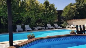 A swimming pool with white lounge chairs and potted plants. - 'Horloge' La Grange du Moulin - Exclusively families, heated pool, garden, wifi (Saint-Pierre-de-Juillers)