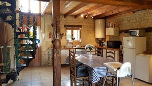 A rustic kitchen with a wooden table, chairs, a microwave, and a refrigerator. - 'Horloge' La Grange du Moulin - Exclusively families, heated pool, garden, wifi (Saint-Pierre-de-Juillers)