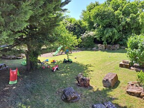 Children can play freely in this well-maintained lawn surrounded by mature trees and a wooden bench for adult supervision.