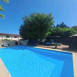 Ein rechteckiger Swimmingpool mit klarem, blauem Wasser, umgeben von einer gefliesten Terrasse.