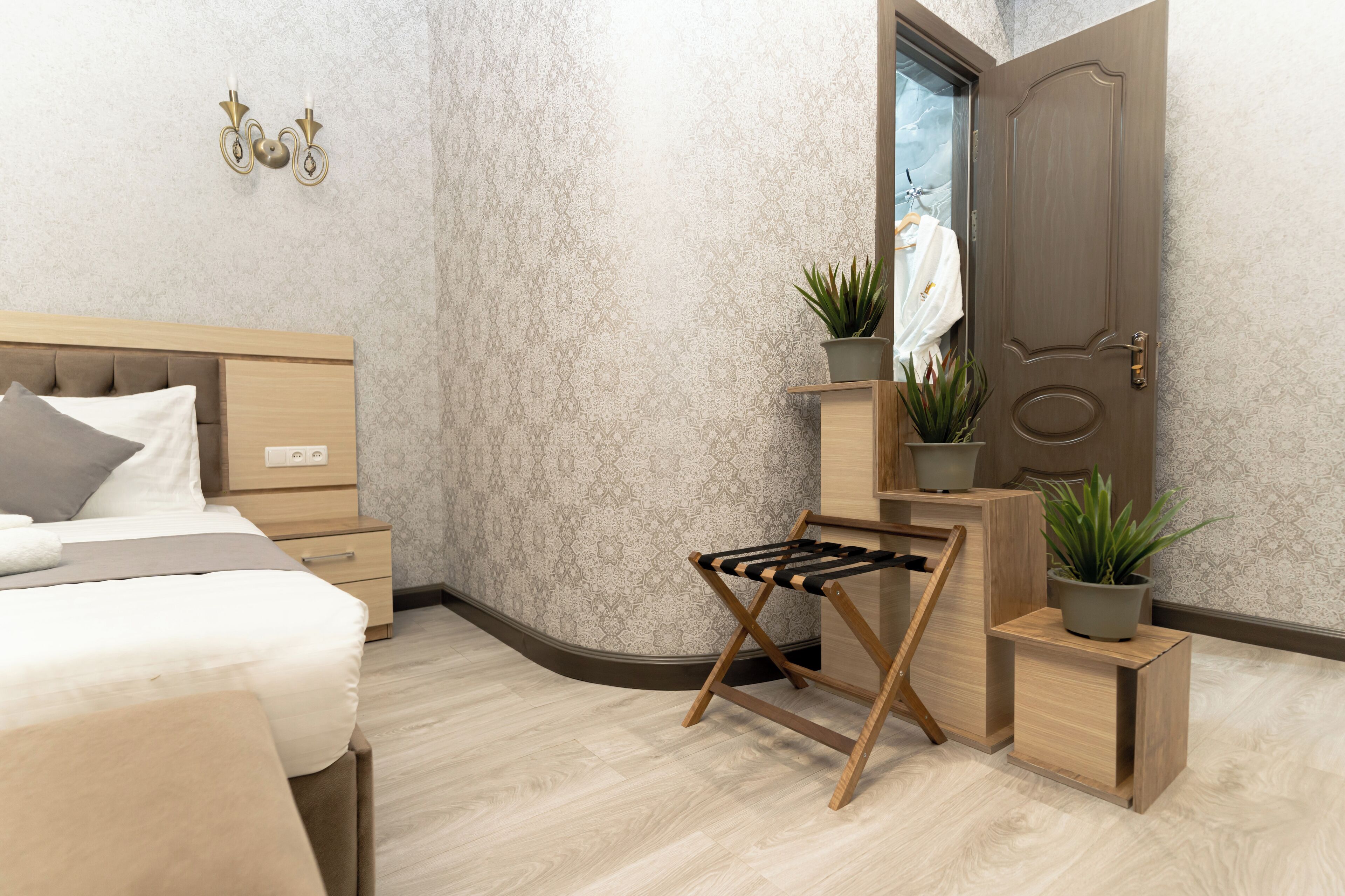 A modern bedroom with a bed, bedside table, and a wooden bench with a black seat.