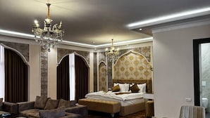 Une chambre d’hôtel spacieuse, dotée d’un grand lit, d’un canapé, d’une table à manger et d’un lustre.