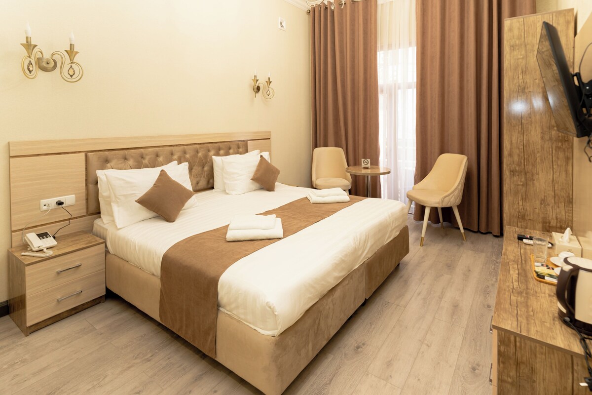 Een hotelkamer met een groot bed, nachtkastjes, een bureau, een stoel en een televisie.