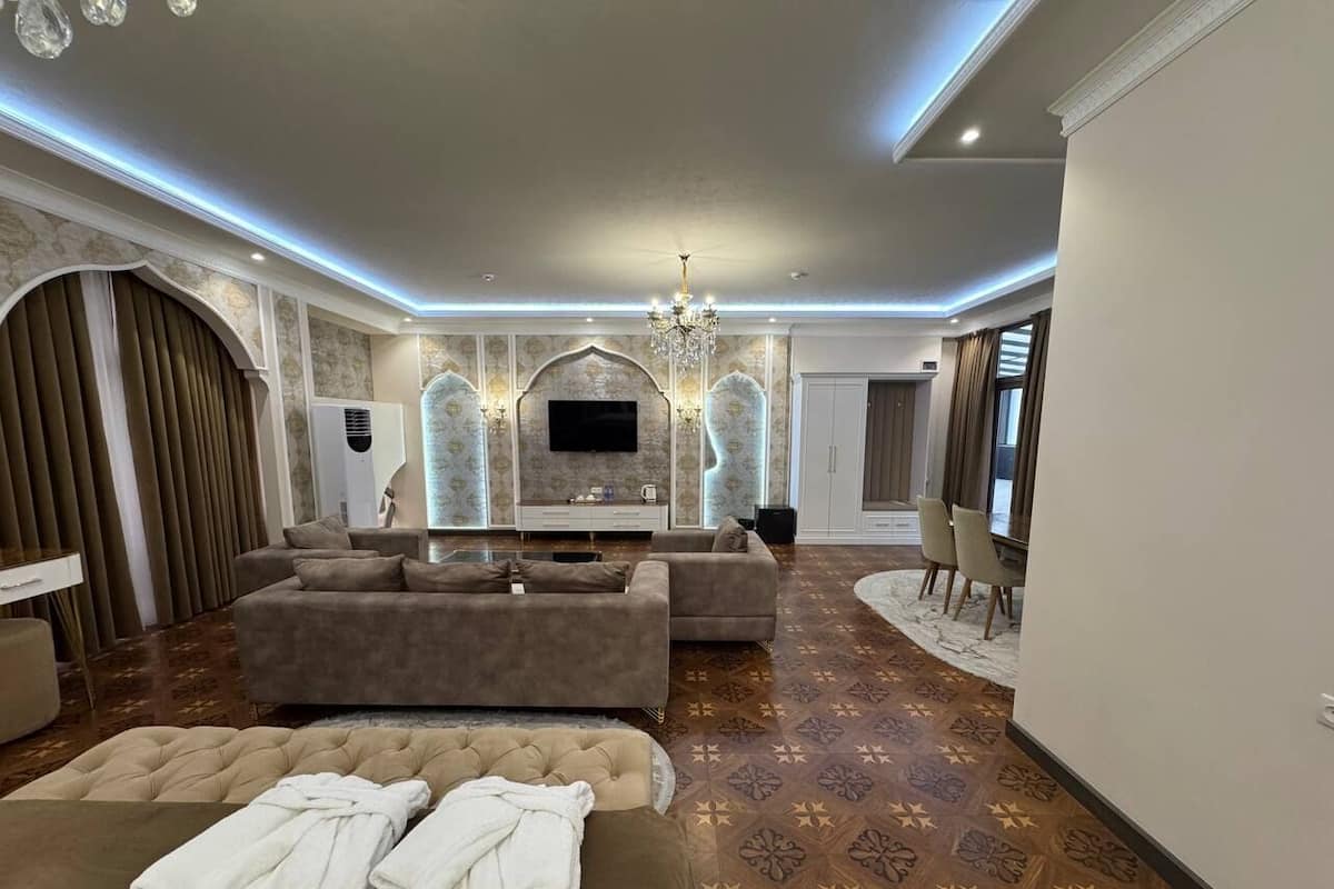 A spacious living room with a large sofa set, a flat-screen TV, and a fireplace.