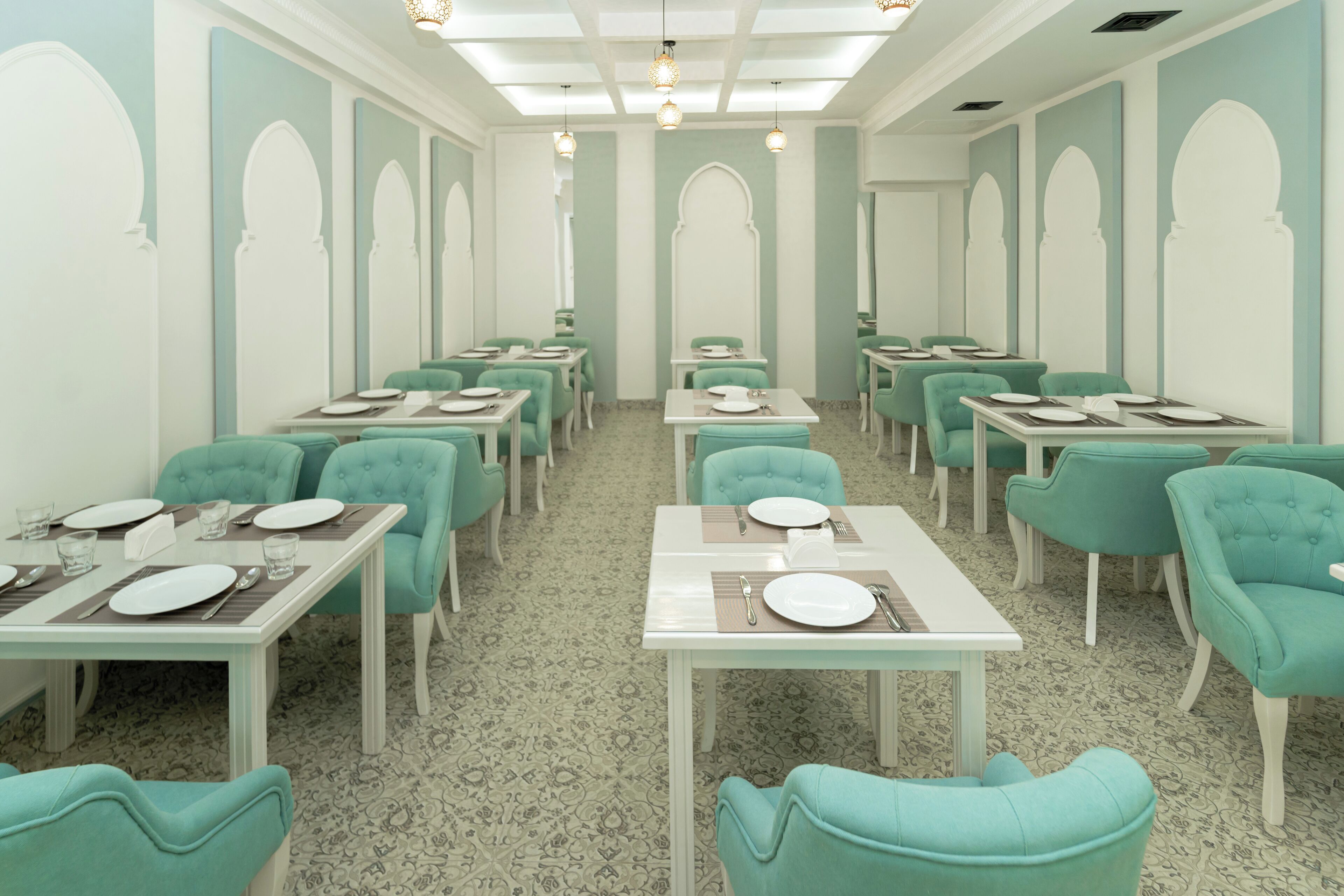 Un comedor con sillas azul verdosas y mesas blancas, cada conjunto con platos y cubiertos.