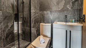 Een moderne badkamer met een douchecabine van glas, een toilet en een wastafel met kastjes.