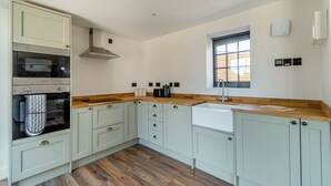 Een moderne keuken met lichte kasten, een ingebouwde oven, een magnetron en een raam dat natuurlijk licht biedt.