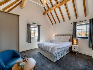 A bedroom with a bed, a bedside table, a chair, a coffee maker, and a window with curtains. - Stable View Barn - UK45938 (Corley)