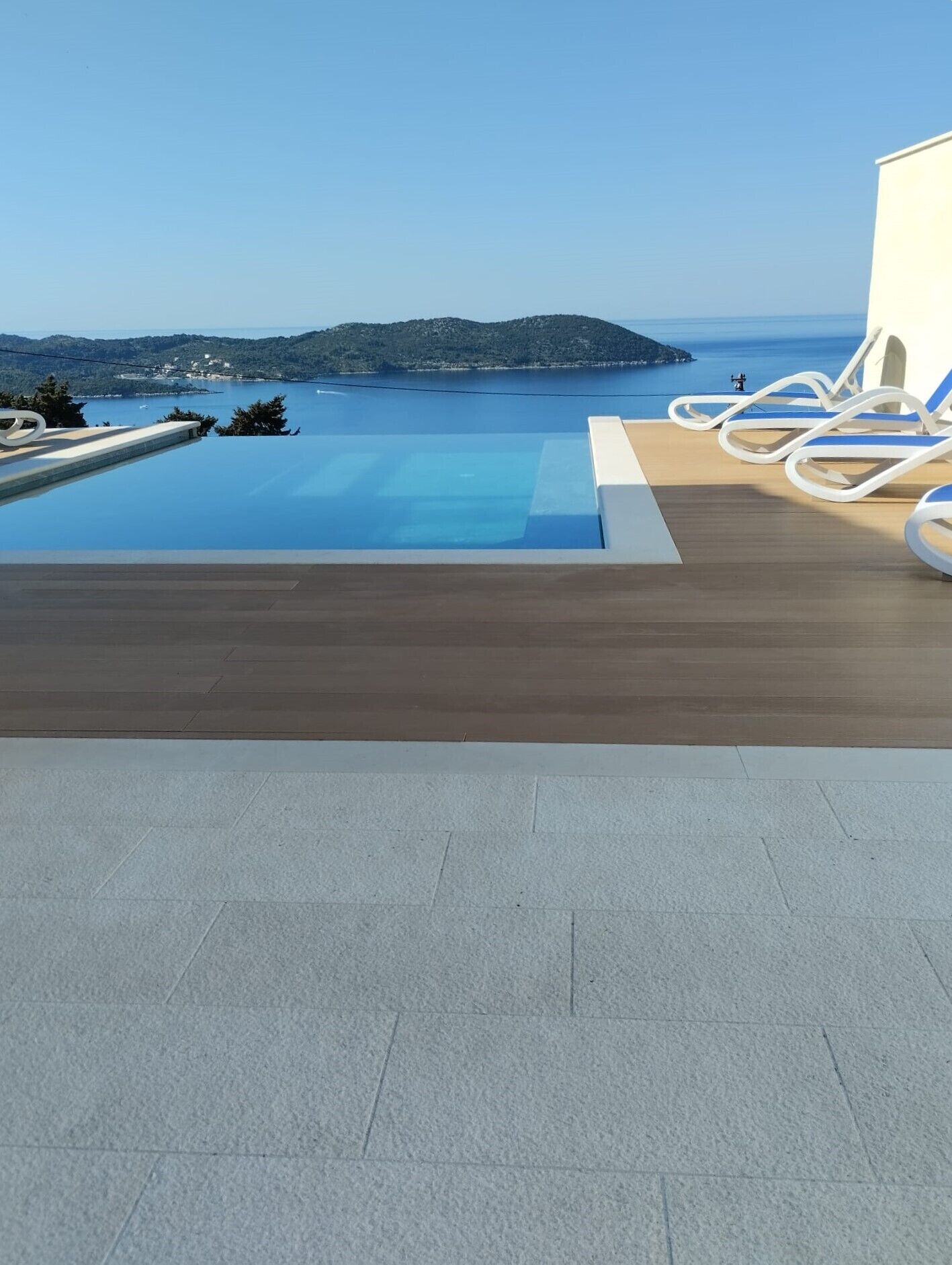 A rooftop infinity pool with a view of a distant island and sea.