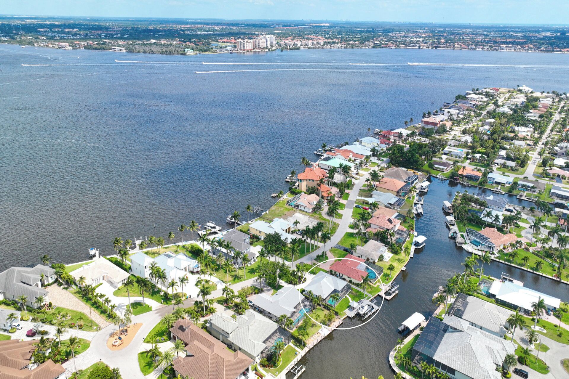 Vue aérienne d’une zone résidentielle côtière, avec des maisons, une marina et une vaste étendue d’eau.