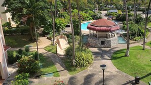 A gazebo with a red roof, surrounded by a well-maintained garden with palm trees and a swimming pool. - Fisherman's Point Ocho Rios (Ocho Rios)