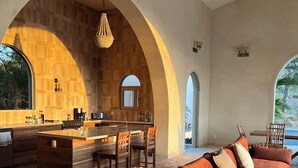 A spacious living area with a large sofa, a dining table with chairs, and a kitchen area with a bar. - Surf, Sun, Serenity! Luxury Private NEW Villa w/ Pool, Ocean and Valley Views.  (San Juan del Sur)