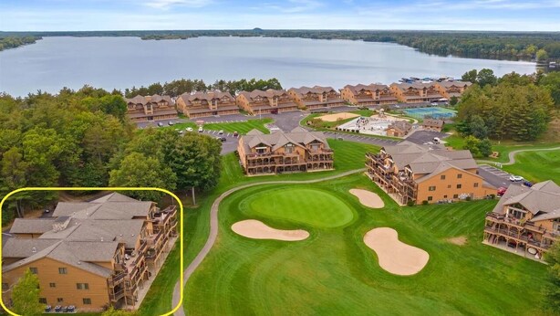 Un complexe hôtelier comprenant plusieurs bâtiments, un terrain de golf et offrant une vue sur un lac.