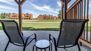 Un espace extérieur aménagé, abrité et doté de deux chaises et d’une petite table, offrant une vue sur un vaste ensemble de bâtiments dotés de nombreux balcons.