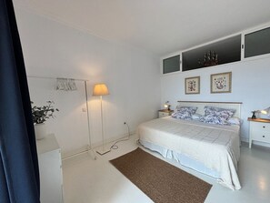 Een slaapkamer met een bed, nachtkastjes, een vloerlamp en wanddecoratie.