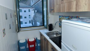A compact kitchen with a window view, a sink, and two waste bins labeled for different types of trash. - La Brezza Home (Piano di Sorrento)