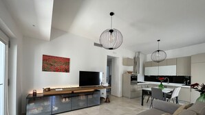 A modern living room with a sofa, TV, and dining area. - Borgo Morgicchio (Carovigno)