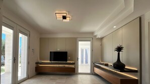 A modern living room with a flat-screen TV, built-in shelves, and a vase on a console table. - Borgo Morgicchio (Carovigno)