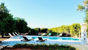 A pool area with lounge chairs and a white structure. - Borgo Morgicchio (Carovigno)