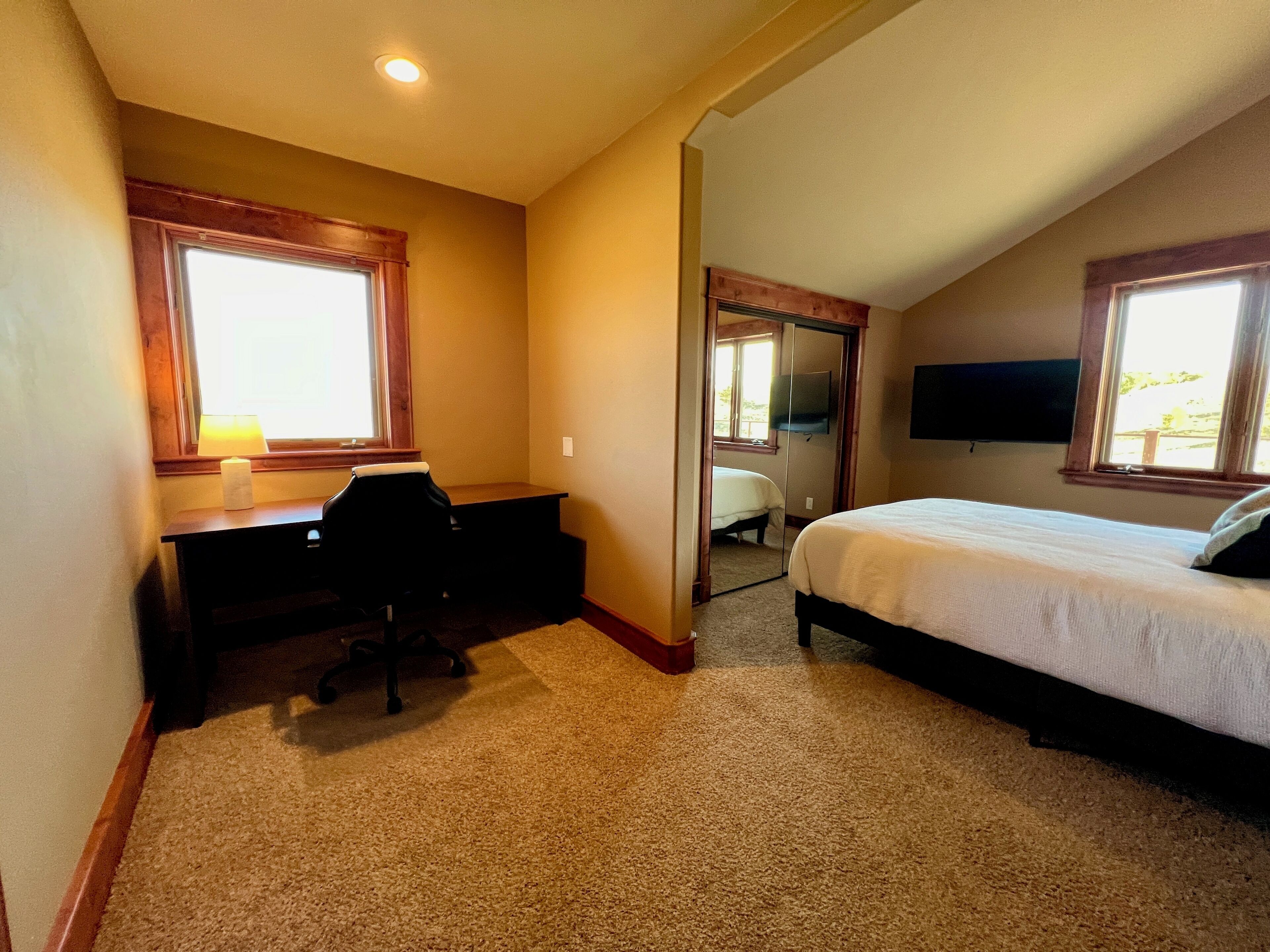 A bedroom with a bed, a desk, and a chair.