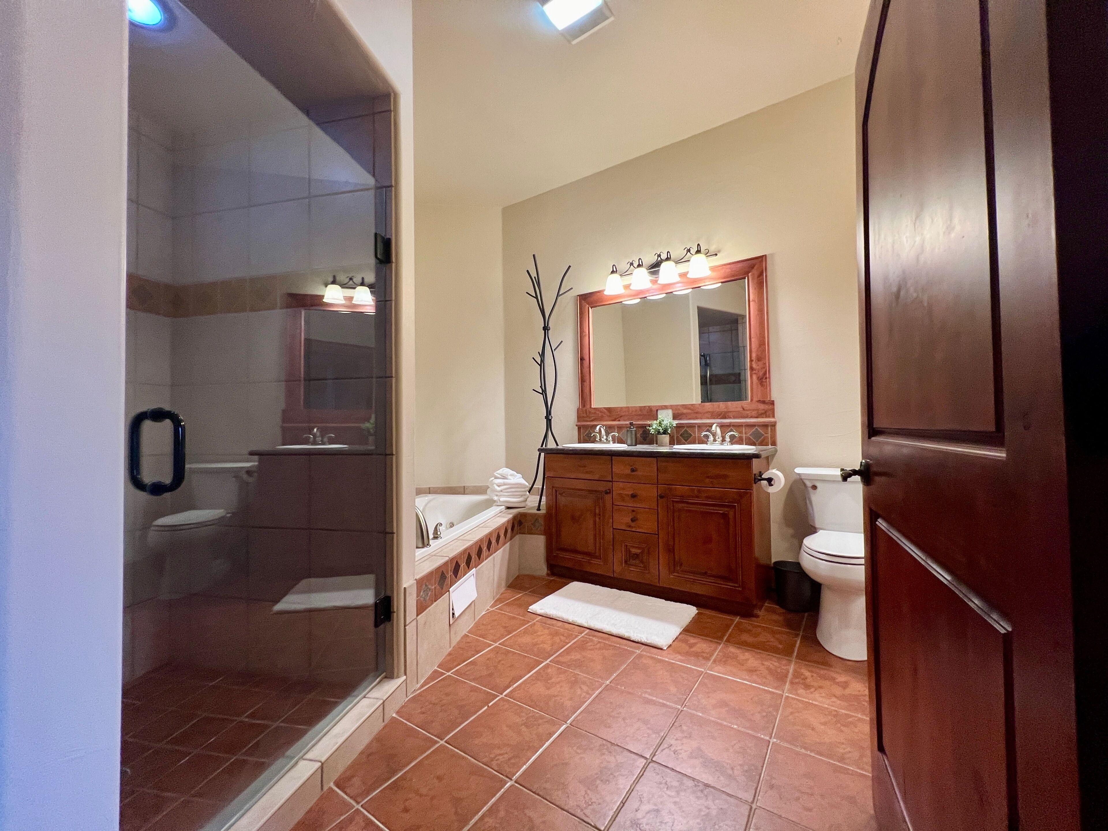 A bathroom with a glass-enclosed shower, a wooden vanity with a mirror, and a white toilet.
