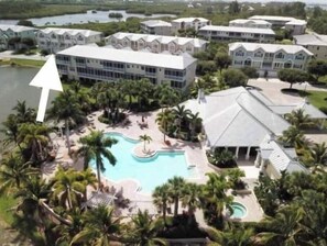 A resort with a large swimming pool surrounded by palm trees and a body of water. - Modern gated renovated 3BR townhome near beaches & Boca G with resort amenities! (Placida)