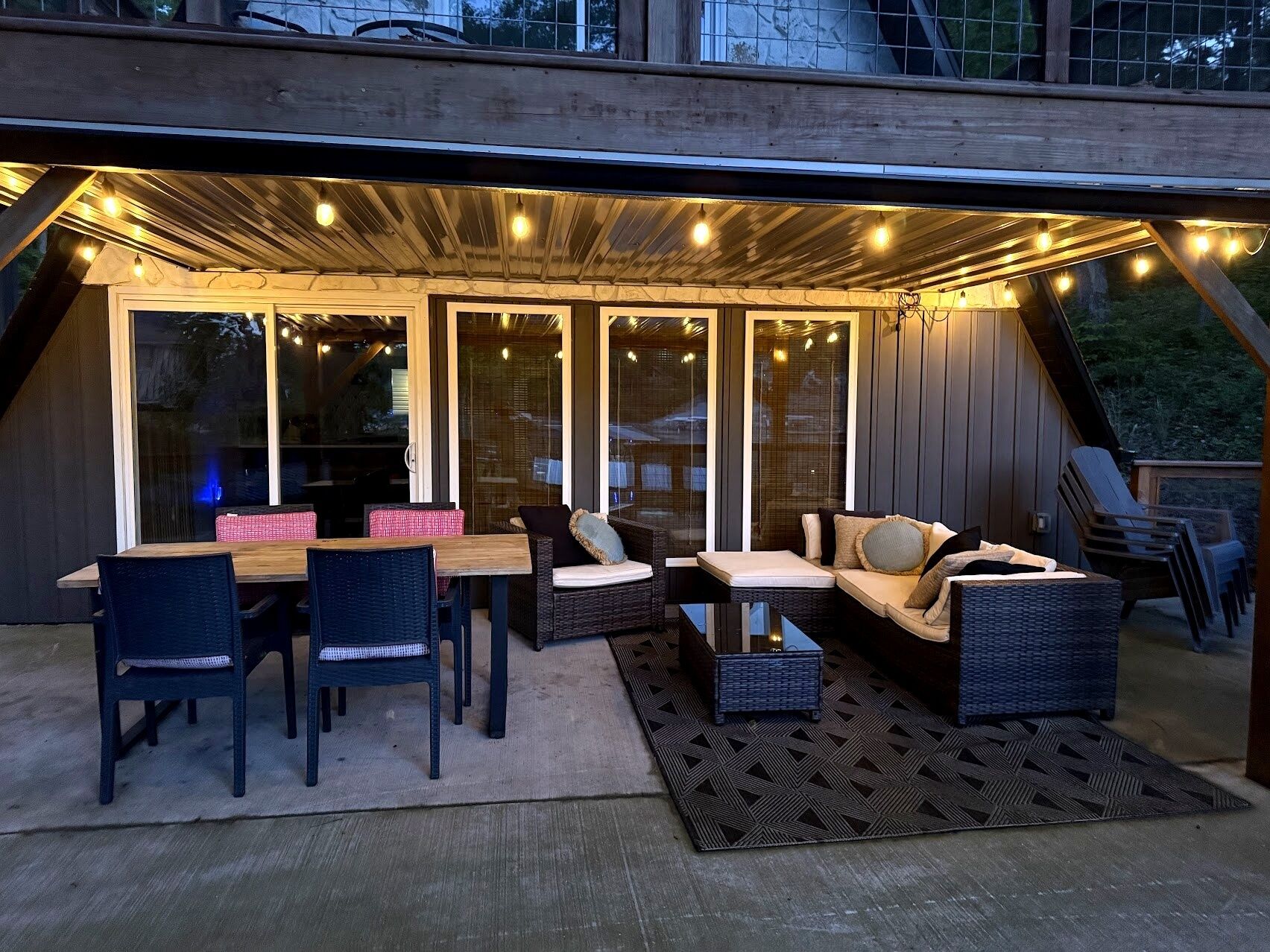 Un área de estar al aire libre con una mesa y sillas, un sofá y un tapete estampado.