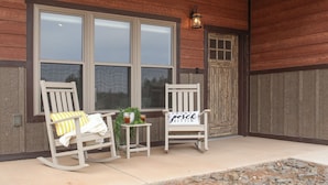 A porch with two rocking chairs, a small table with a plant, and a sign that reads "front porch sittin'".